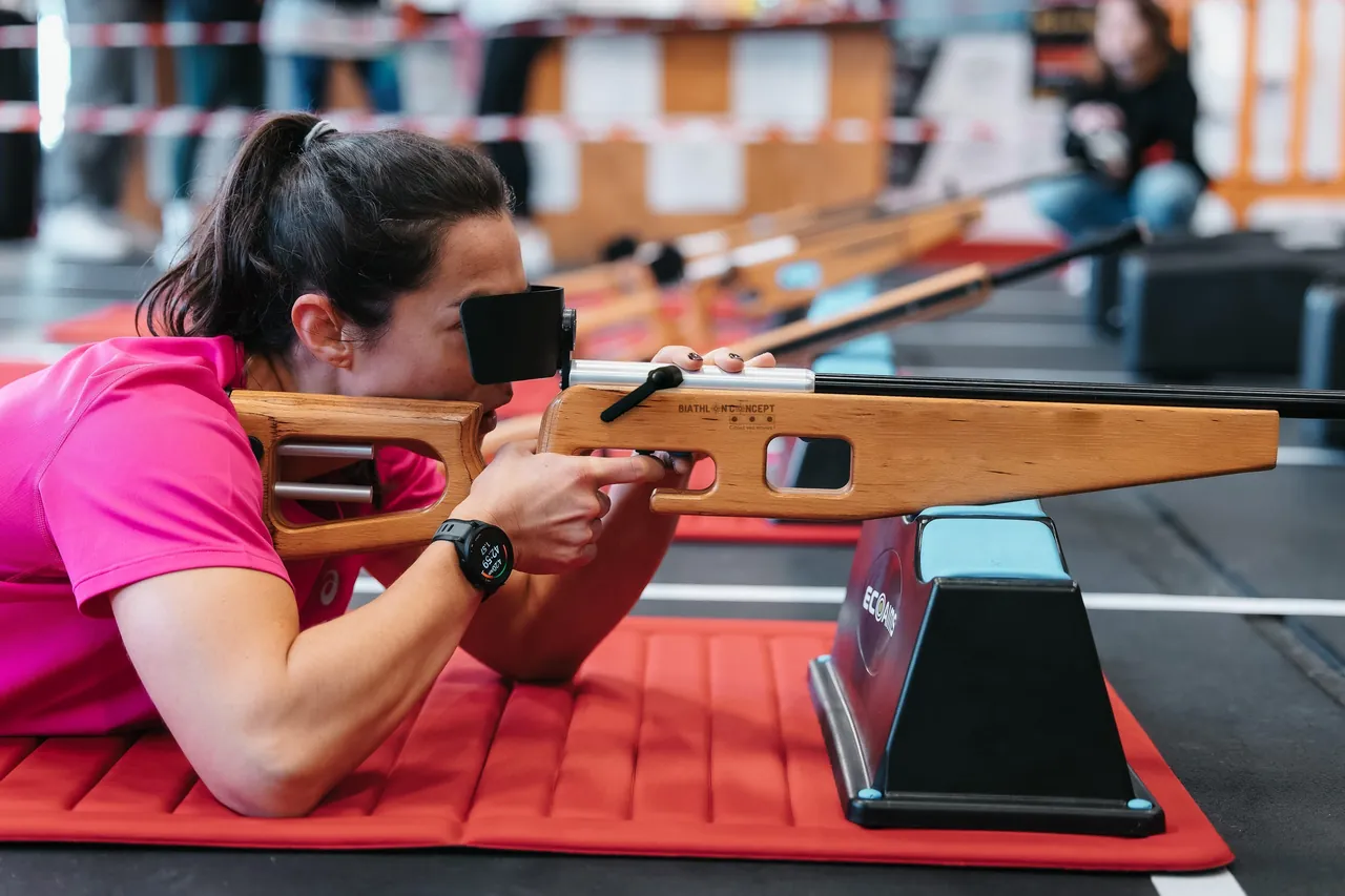 Participante en position couchée sur un tapis rouge, visant avec une carabine laser Biathlon Concept, levier d'armement sur le côté